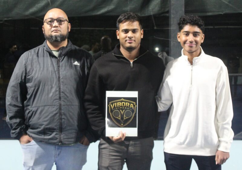 A group of padel players are photographed on a padel court at night.