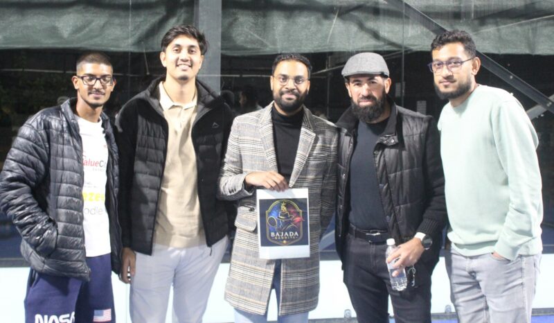 A group of padel players are photographed on a padel court at night.