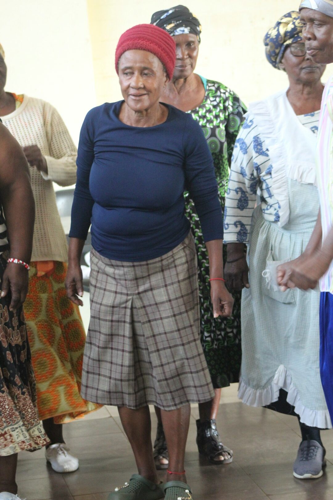 A group of women are photographed dancing inside a community hall.