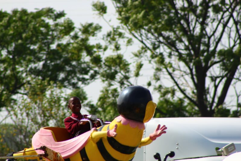 A young child is photographed having fun while on a Bee ride at a loal fair.
