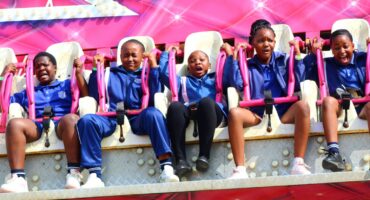 A group of school children dressed in blue uniforms are visibly scared while on a carnival ride.
