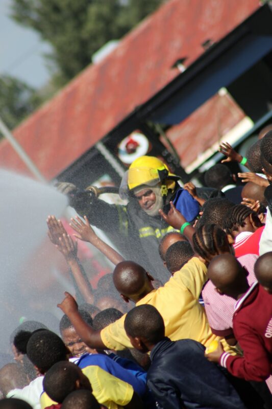 A firefighter is pictured allowing the children to play in the water.