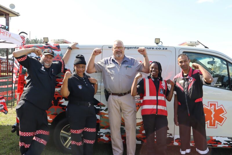 A team of paramedics wearing red and black attire pose for a photo.