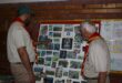 Two Scouts looking at a photo board of past events and members.