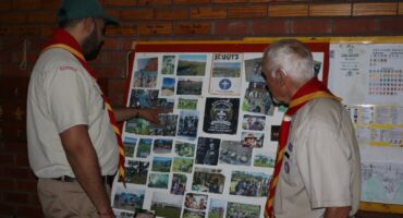 Two Scouts looking at a photo board of past events and members.