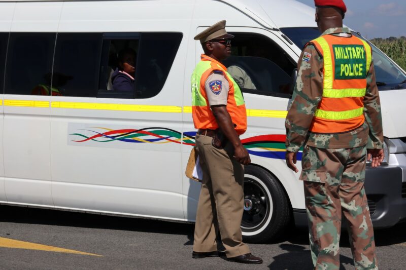 A Road Traffic Inspectorate officer and a Military Police Officer next to a taxi.