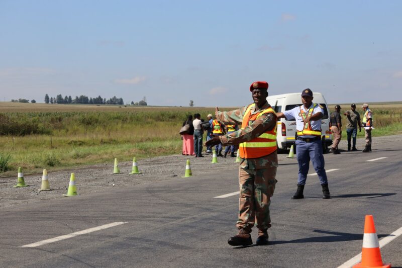A military police officer is showing a vehicle to pull over during a roadblock.