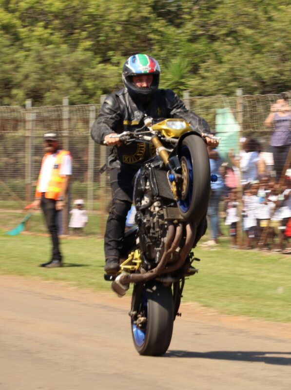 Motorcyclist performs wheelie stunt before watching crowd