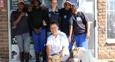 A group photo of Jenavieve Tinkler with the dedicated SPCA staff and two of their office pets.