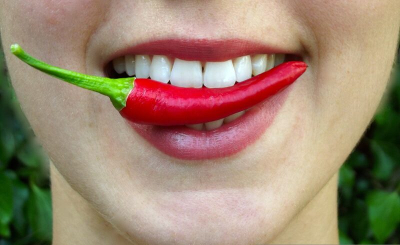 A woman with a chilli pepper between her teeth