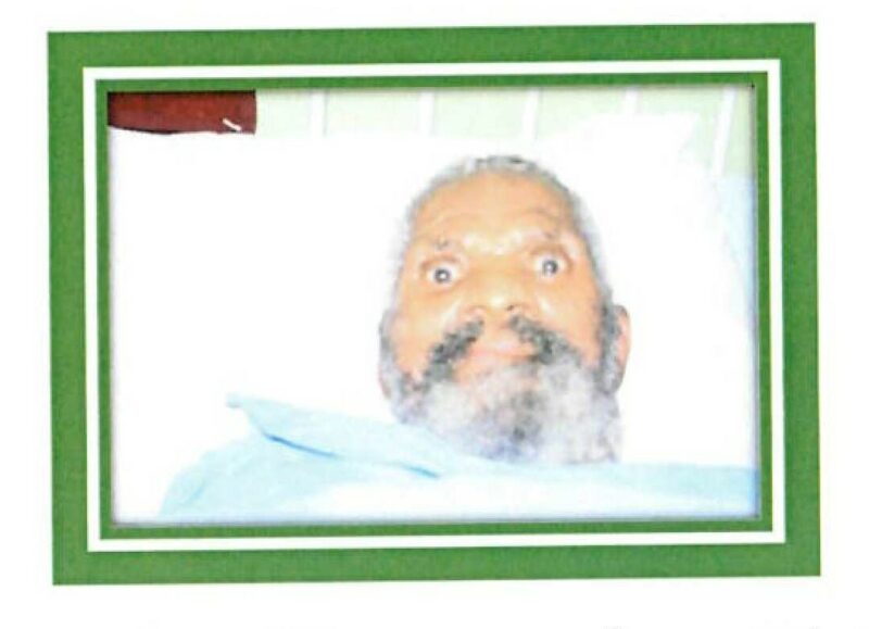 An image of a male patients, with grey hair and a grey beard laying in a hospital bed.