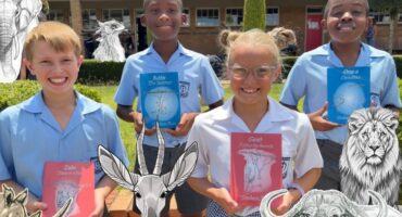 An image of Michaelis learners proudly holding donated books by Graham Root.