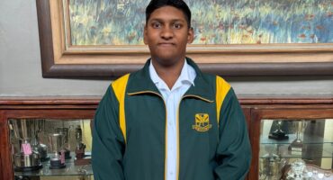 Image of Vryheid High School learner dressed in his uniform standing in an office.