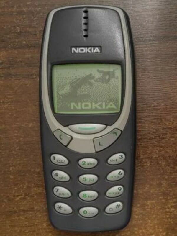 A cellphone named the Nokia 3310 on a wooden surface.