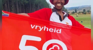 Image of a woman who completed her 50th parkrun, holding a banner.