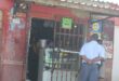 Photof of a SAPS officer in front of a shabby tuckshop type building in Glencoe, KZN.