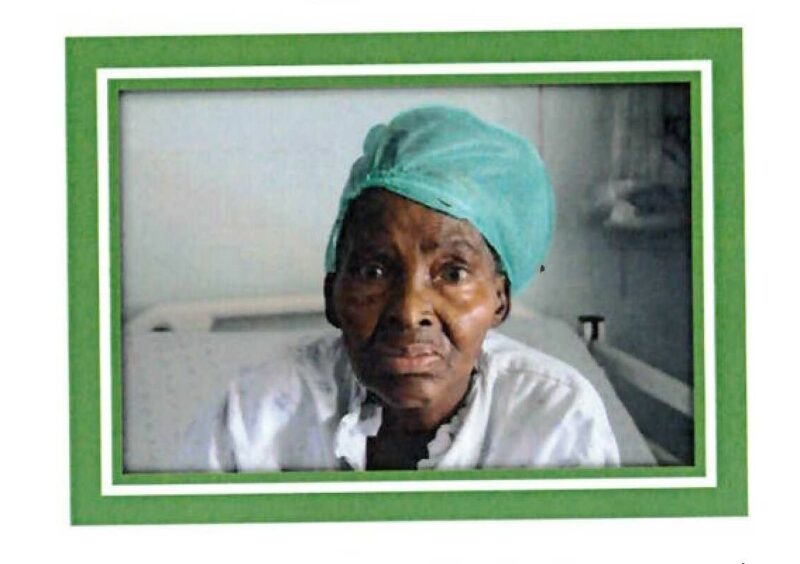 An image of an elderly woman with a green hospital cap on her head in a hospital room.