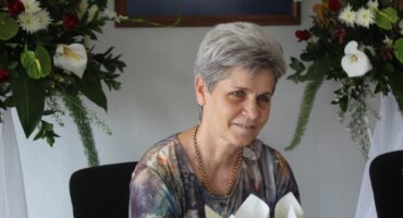 Image of an elderly woman sitting at a table while tearful.