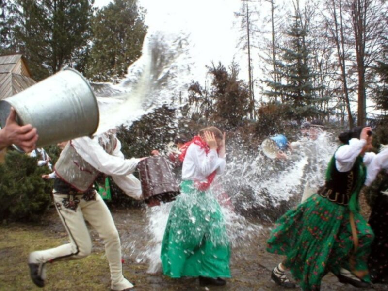 People in traditional Polish clothing throwing each other with buckets of water.