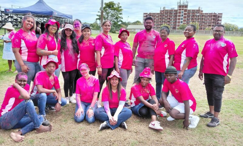 Various grown ups pose for a photo outside while dressed in red attire.