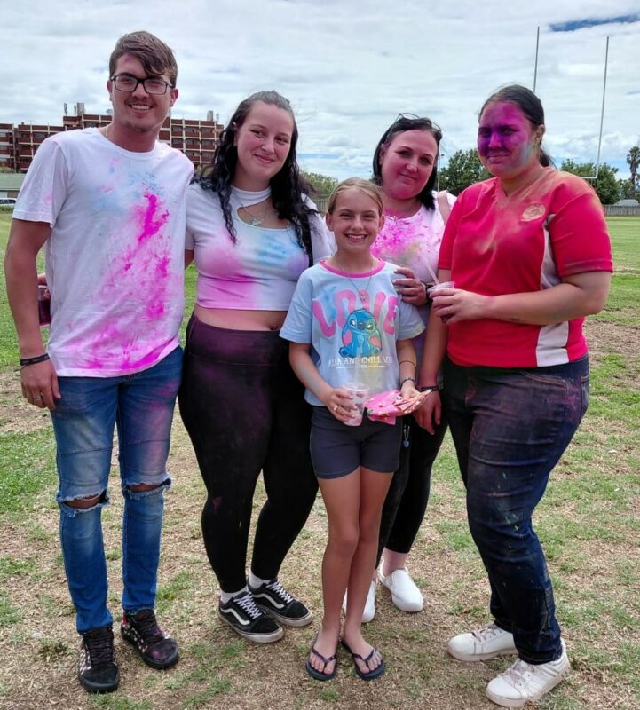 A photo of a group of people enjoying throwing colour powder during a colour run fun day.