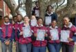 A group of scholars are photographed outside holding their certificates.