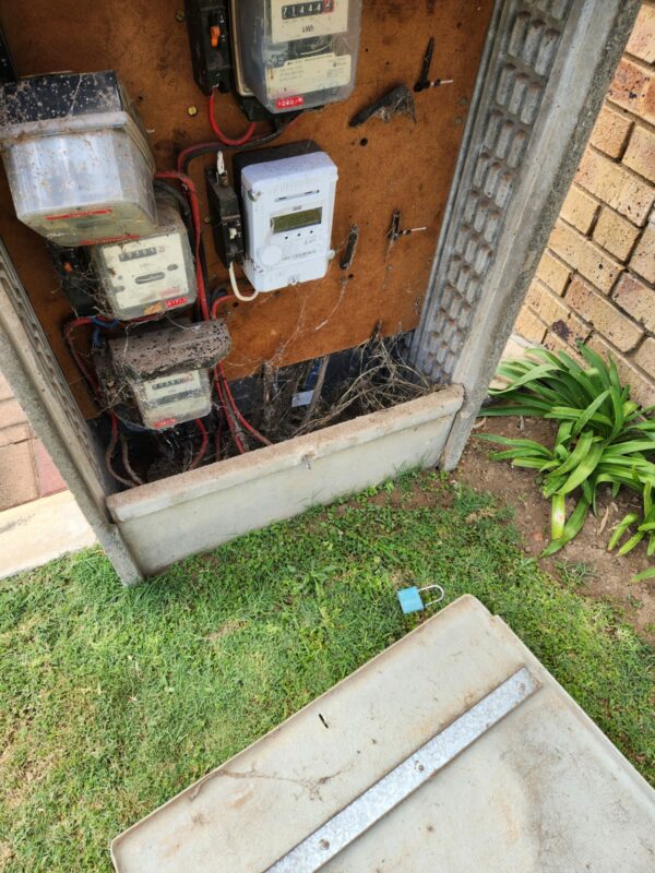 A power box that has been broken into while cables have been cut. A lock is seen lying next to the broken cover.