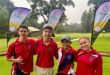 A photo taken of four young golfers posing in red attire on a golf coarse.