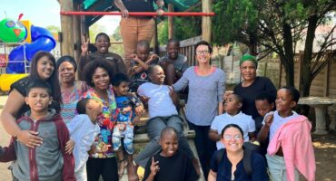 Children and staff smile on playground at special needs school