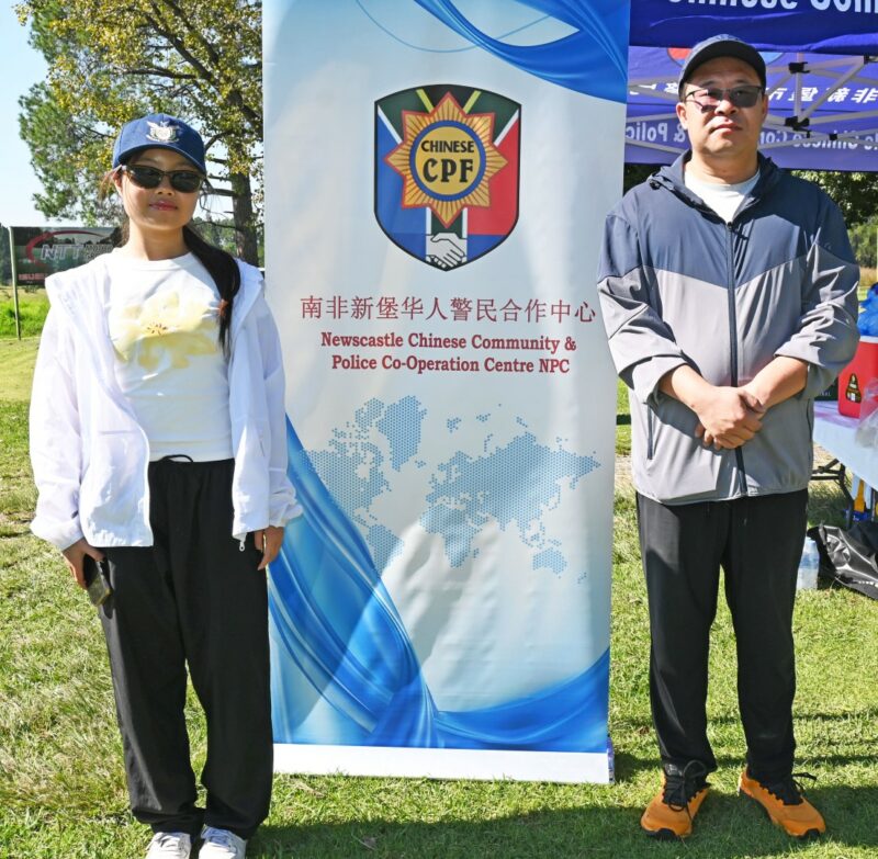 Two men are photographed standing next to a banner on the golf coarse.