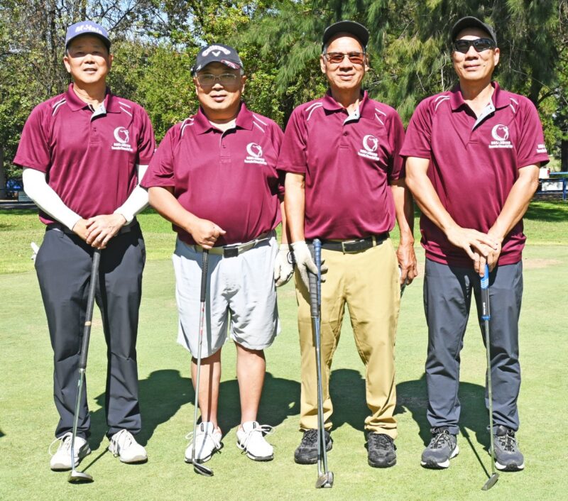 A group of men, dressed in golfing attire are photographed on a golf coarse.
