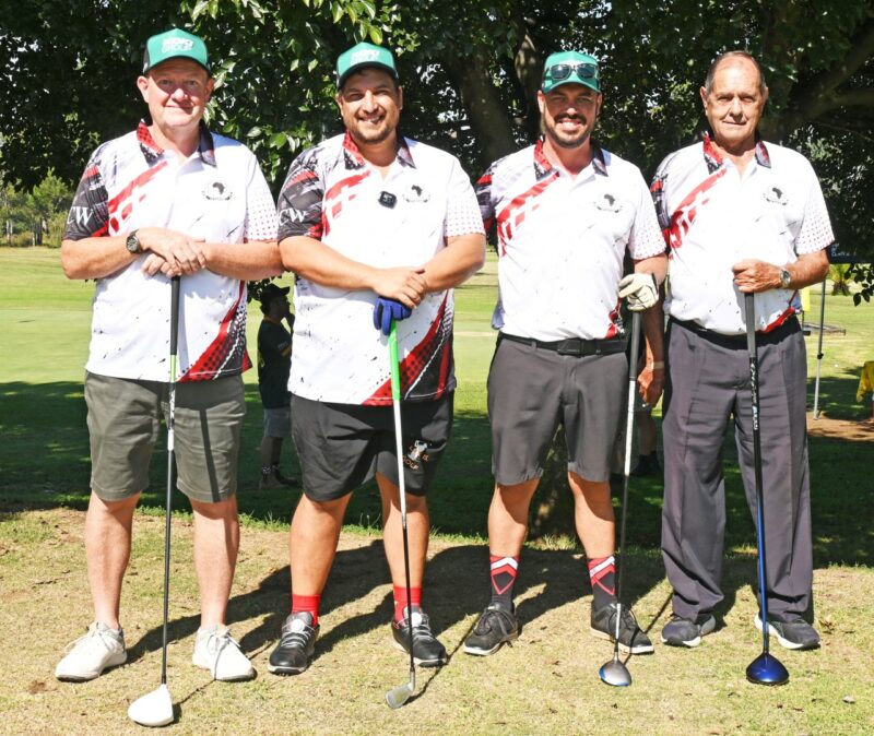 A group of men, dressed in golfing attire are photographed on a golf coarse.