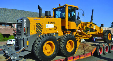 Image of municipal grader on a flat bed arriving in Dundee.