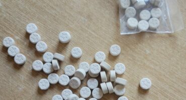 Image of mandrax tablets loose and in a packet on a table.