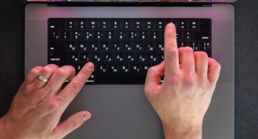 Male hands on laptop keyboard. Man typing on laptop. Top view. High quality photo. Close-up of male hands typing on keyboard. Online work concept. Man working on laptop.
