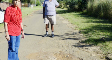 Image of a couple inspecting huge potholes in the Glencoe area.