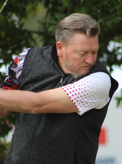 A golfer is photographed outsde on the golf coarse.