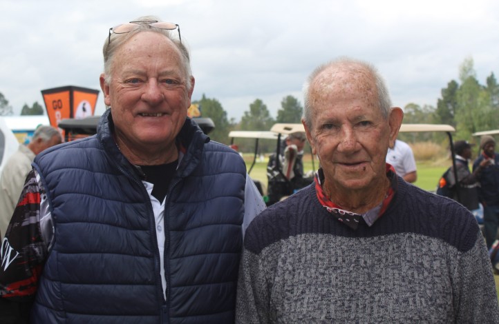 Two golfers are photographed outsde on the golf coarse.