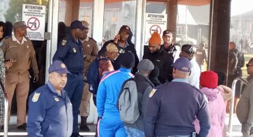 Image of SAPS officers and officials monitoring protesters outside the Dundee municipal offices.
