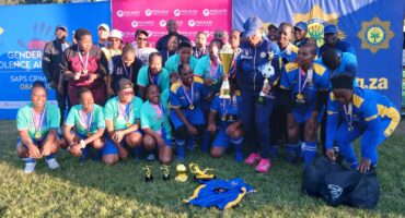 Image of SAPS ladies football team celebrating with trophy.
