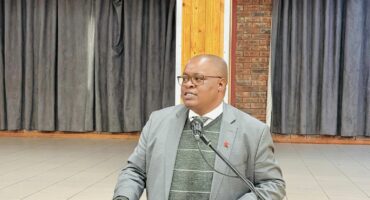An image of AbaQulusi Local Municipality Mayor, speaking on a microphone at Cecil Emmett Hall where he presented the 2026/27 IDP and draft budget to the residents of wards 8,9 and 10.