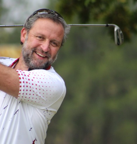 A golfer is photographed outsde on the golf coarse.
