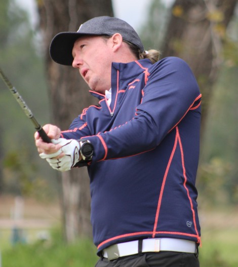 A golfer is photographed outsde on the golf coarse.