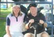 Two men are pictured on a golf cart during the annual Albatros Golf Day. Both men are wearing golf attires with golf clubs behind them.