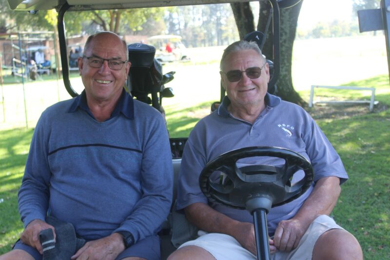 Two men are pictured on a golf cart during the annual Albatros Golf Day. Both men are wearing golf attires with golf clubs behind them.
