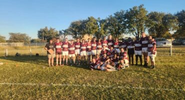 Image of group of rugby players in maroon rugby jerseys after a game.