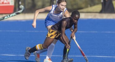 Image of two girls on an astro hockey pitch in a one on one chase.