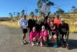 Image of group of runners standing on a tar road.