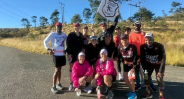 Image of group of runners standing on a tar road.