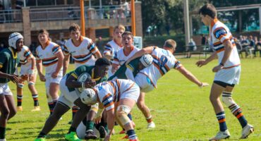 Image of 2 rugby teams tackling during a game.